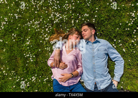 Happy young couple relaxing on grass in a park, overhead view Stock Photo