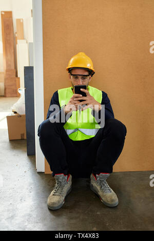 Worker using cell phone during a break in factory Stock Photo