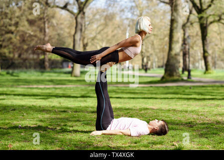 Young couple doing yoga acrobatics in an urban park Stock Photo
