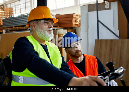 Two men with forklift in factory Stock Photo