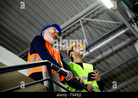 Two workers standing on upper floor in factory Stock Photo