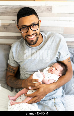 Portrait of happy father holding his newborn baby in bed Stock Photo