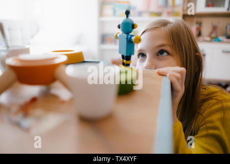 Girl at home looking at toy robot Stock Photo