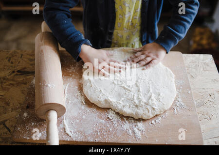 Girl's hands kneading dough, partial view Stock Photo
