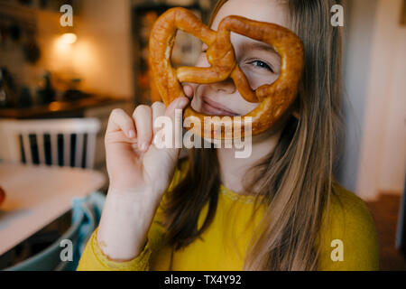 Girl in kitchen holding pretzel Stock Photo