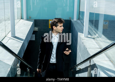 Businessman with cell phone walking up stairs in the city Stock Photo