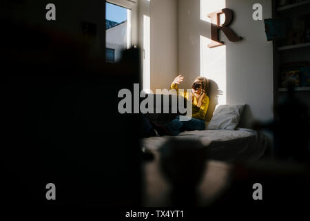 Girl at home shielding her eyes from sunshine Stock Photo