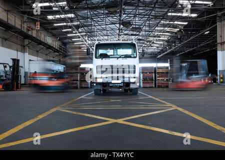 Parked truck in warehouse and moving forklifts