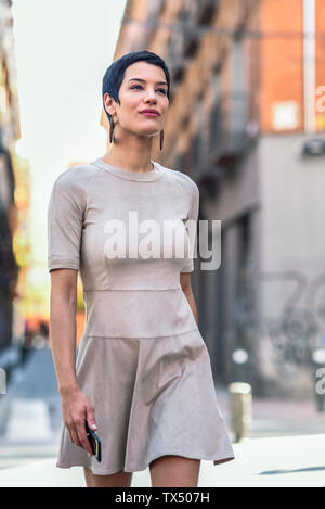 Fashionable young woman wearing a dress walking in the city Stock Photo