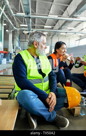 Workers in factory having lunch break together Stock Photo