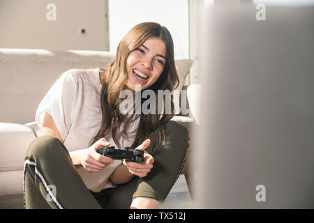 Happy young woman playing video game at home Stock Photo