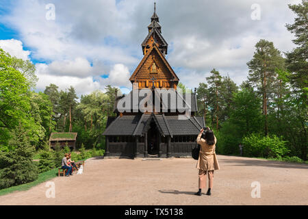 Norway Folk Museum, rear view of a female tourist taking a photo of a Norwegian stave church sited in the Norsk Folkemuseum in the Bygdøy area of Oslo. Stock Photo