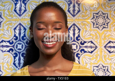 Portrait of a happy young woman at a tiled wall Stock Photo
