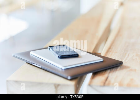 Stack of mobile devices on wooden bench Stock Photo