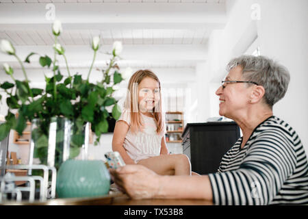 Happy grandmother with cell phone and granddaughter at home Stock Photo