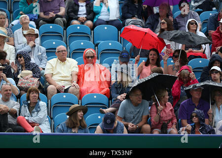 Eastbourne, UK. 24 June 2019 Spectators shelter from the rain during Day three of the Nature Valley International at Devonshire Park. Credit: James Boardman / Alamy Live News Stock Photo