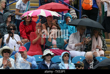 Eastbourne, UK. 24 June 2019 Spectators shelter from the rain during Day three of the Nature Valley International at Devonshire Park. Credit: James Boardman / Alamy Live News Stock Photo