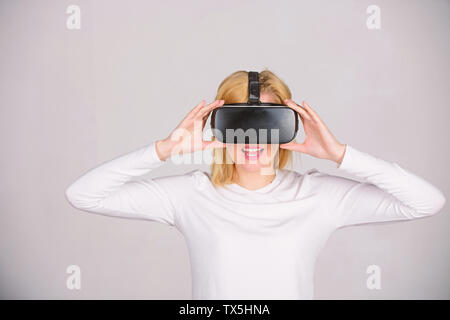 Woman using virtual reality headset. Woman watching virtual reality vision. Beautiful woman wearing virtual reality goggles in studio. Future is right now Stock Photo