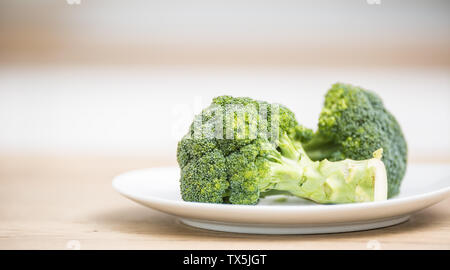 Fresh green broccoli in plate on kitchen wooden board. Stock Photo