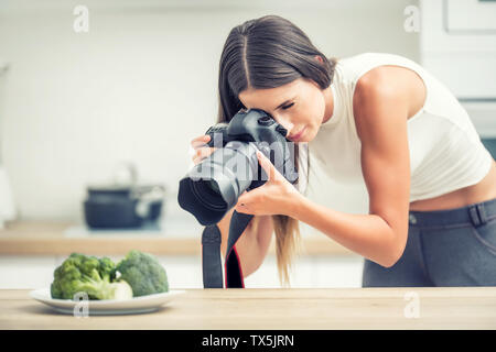 Woman professional photographing plate with broccoli. Food photographer working in kitchen studio. Stock Photo