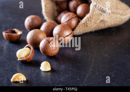 Australian macadamia nuts poured out of bag on black table Stock Photo