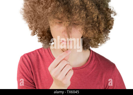 Portrait of a young curly European man looking worriedly at his long hair. holds a curl of hair with his fingers. very lush male guy hair. curling hai Stock Photo