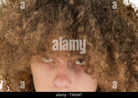 portrait of a young curly European man with a serious look looking at his long hair with his eyes up. very lush male guy hair. curling hair for men. Stock Photo