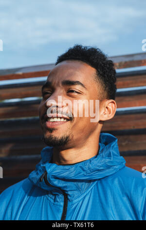 Close up of a young african man wearing hooded jacket standing outdoors Stock Photo