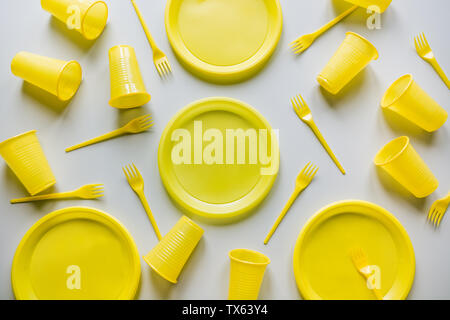 Single use yellow picnic utensils on grey. Environment, eco friendly, discarded, plastic garbage for recycle concept.Top view. Flat lay. Pattern. Stock Photo