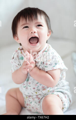 Lovely baby girl sitting on the bed to play Stock Photo - Alamy