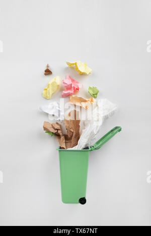Trash bin with paper waste on a gray background. Recycling concept Stock Photo