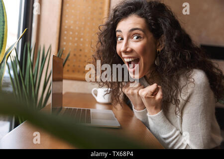 Emotional cute girl using laptop while lying on green floor at home ...
