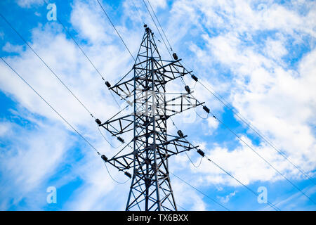 a high voltage power pylons against blue sky and sun rays Stock Photo ...