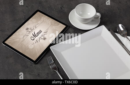 Tablet with stylish restaurant logo and laid table  Stock Photo