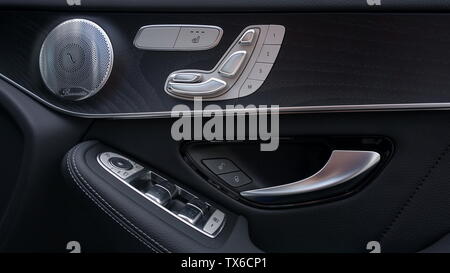 Driver's door panel in right hand drive car showing seat and mirror controls, window switches and speaker Stock Photo