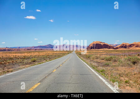 Monument Valley road, Navajo Tribal Park in the Arizona-Utah border, USA. Scenic highway to red rock formations, blue clear sky in spring Stock Photo