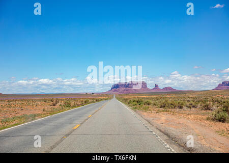 Monument Valley road, Navajo Tribal Park in the Arizona-Utah border, USA. Scenic highway to red rock formations, blue clear sky in spring Stock Photo