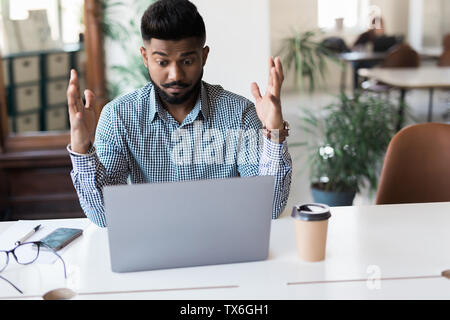 Angry Indian businessman screaming over laptop in office. Stock Photo