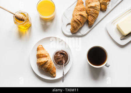 Freshly baked croissants and cup of coffee on white. Space for text. French breakfast. View from above. Stock Photo