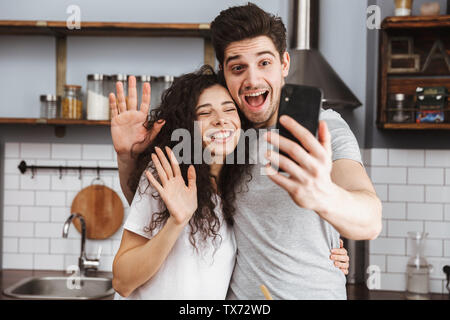 Cheerful couple cooking at the kitchen, having fun, taking a selfie Stock Photo