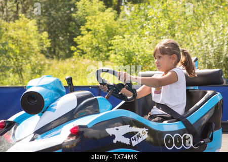 Little girl rides on toy electric cars in the Park Stock Photo