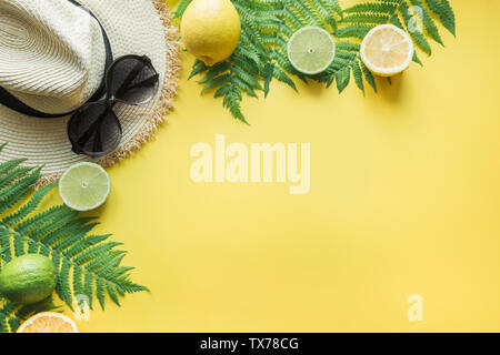 Female beach straw sunhat, sunglasses, citrics on punchy yellow. Top view and space for text. Summer travel concept. Stock Photo