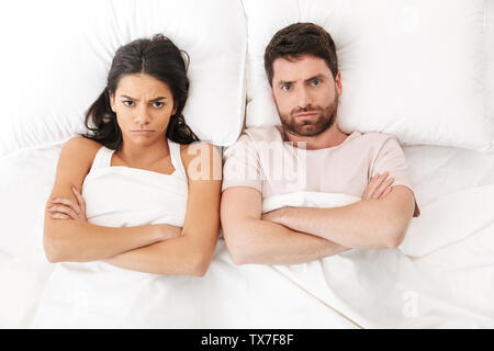 Portrait of a beautiful young couple laying in bed, top view, having an argument Stock Photo
