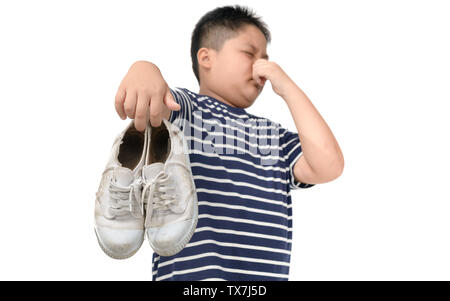 Disgusted fat boy holding a pair of smelly and stinky shoes isolated on white background, Stock Photo