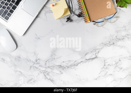 Modern marble desk table with laptop, other supplies with copy space for input the text in the middle. Top view, flat lay. Stock Photo