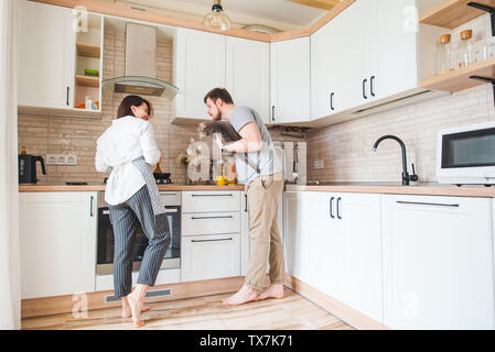 man with woman at the kitchen cooking. holding cat on hands. young family at home Stock Photo
