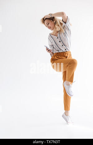 Full length photo of relaxed nice woman dancing and holding cellphone isolated over white background in studio Stock Photo