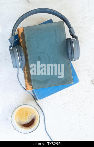 Audio book concept. Headphones with books and cup of coffee on wooden table. Top view Stock Photo