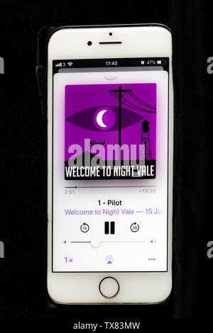 Apple phone showing the podcast Welcome to he night vale playing Stock Photo