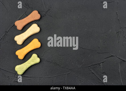 Four bone shaped dog biscuits on a dark background, top view Stock Photo